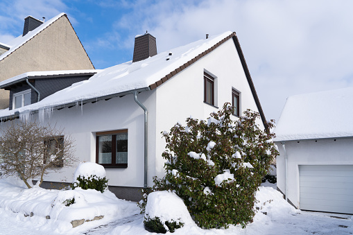 A snow-covered house with icicles on the gutter