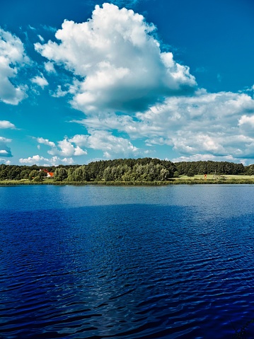The view of a green shore with blue water and cloudy sky