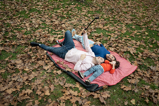Family lying on back enjoying picnic in autumn