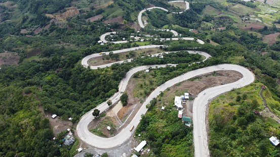 An aerial shot of trucks and cars on a winding road in a forested mountain