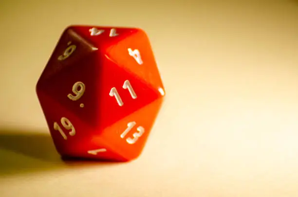 Photo of selective focus 20-sided red dice for role-playing game isolated on warm background