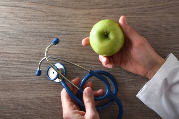 istock Nutritionist doctor with apple and stethoscope in hands on table 1466954826