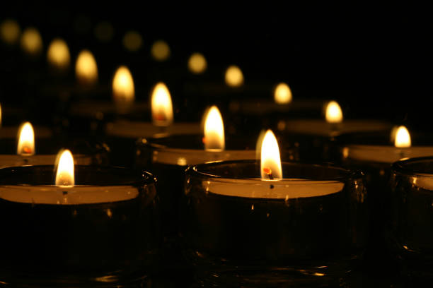 istock Closeup of small candles glowing on a dark background 1466954854