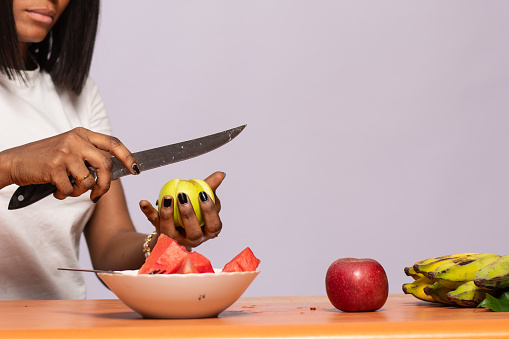 A beautiful Nigerian woman slicing fruits for fruit salad