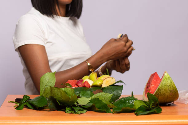 красивая нигерийская женщина готовит фруктовый салат - fruit salad fruit healthy eating making стоковые фото и изображения