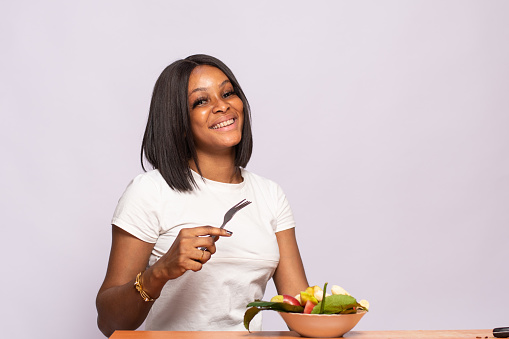 A beautiful Nigerian woman holding fork with a bowl of fruit salad