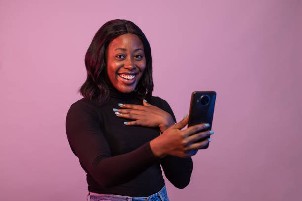 istock Cheerful Nigerian woman using her phone isolated on pink background 1466957497