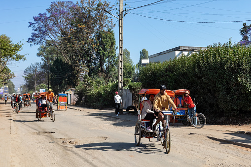 Antsirabe, Madagascar - November 1. 2022: Traditional rickshaw bicycle with Malagasy people on the street of Antsirabe, one of the ways to earn money. Everyday life on the street of Madagascar.