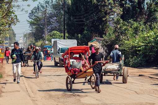 Antsirabe, Madagascar - November 10. 2022: Traditional rickshaw bicycle with Malagasy people on the street of Antsirabe, one of the ways to earn money. Everyday life on the street of Madagascar.