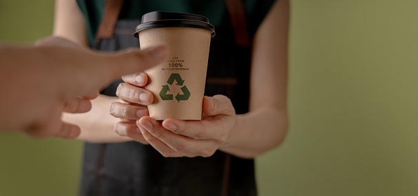 Recycled Packaging Concept. Barista Giving a Hot Cup of Coffee to customer. Zero Waste Materials. Environment Care, Reuse, Renewable for Sustainable Lifestyle. POV shot