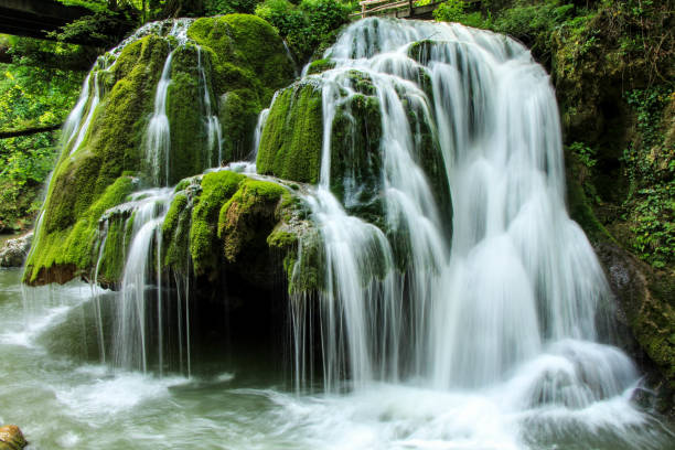 istock Beautiful waterfall coming down from the rocks covered with moss in the park 1466959982