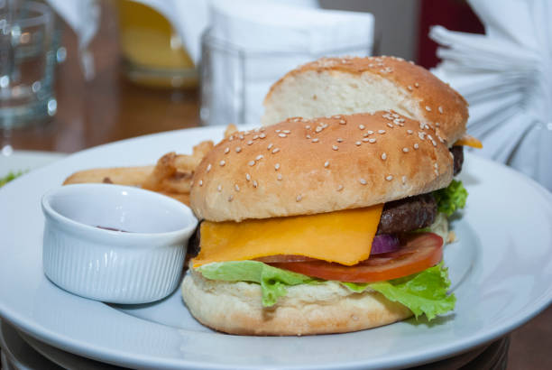 istock Tasty hamburger with lettuce and tomato cheese, served on white plate on table 1466962459
