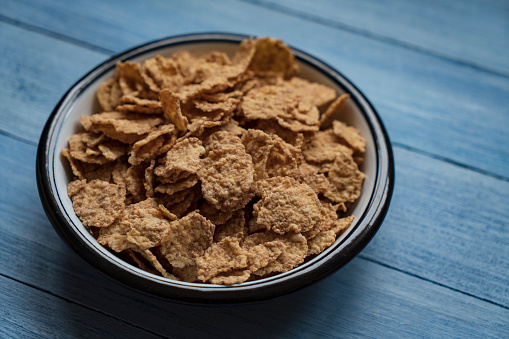 Tasty corn flakes in bowl on wooden background.