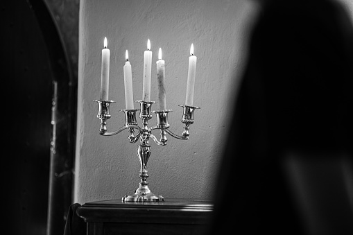 A grayscale shot of antique candlesticks and candles on the table