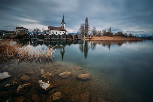 A view of a church reflected on a lake on a gloomy autumn day