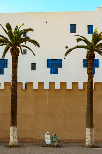 Morocco. Essaouira. Two North African men sitting on a bench in front of the ramparts