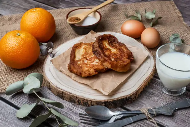 Photo of Torrijas. Typical Spanish sweet on a wooden table made of bread, milk, sugar, eggs, cinnamon and orange zest that is consumed at Easter