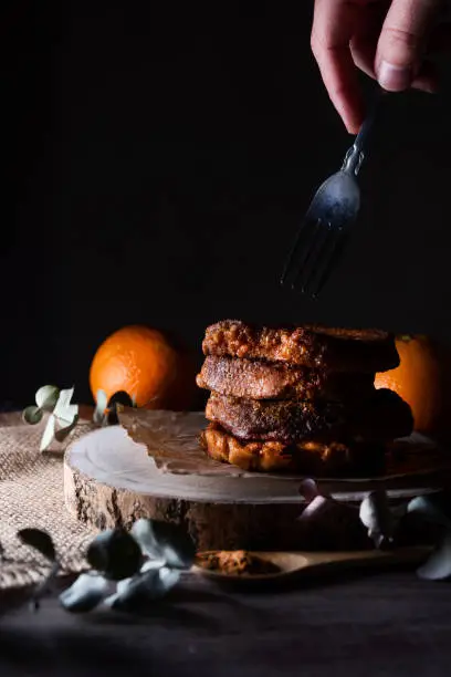 Photo of Torrijas, a typical Spanish sweet made of bread, milk, eggs, sugar, cinnamon and orange zest that is consumed during Carnival and Easter. Dark food photography