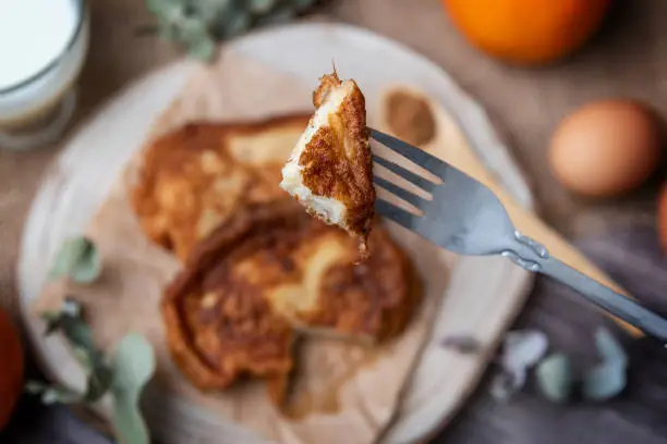 Photo of Torrijas. Close-up of a torrija on a fork, a typical Spanish sweet made of bread, milk, eggs, sugar, cinnamon and orange zest that is consumed during Carnival and Easter
