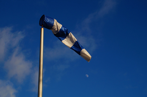 A blue windsock at the old airfield Frankfurt-Bonames against the blue sky with moon and clouds. Beautiful blue and white combination.