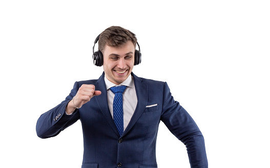 Dancing handsome man in business suit with headphones. The concept of freedom in business. In the studio on a white background. High quality photo