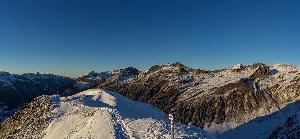 A panoramic shot of rocky mountains covered with snow