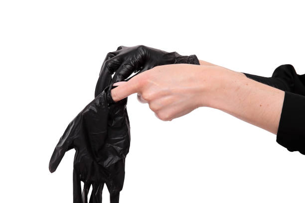 Woman puts on black rubber gloves, only hands on white background Horizontal stock photo