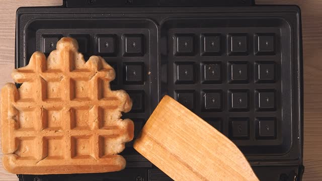 Cooking homemade waffles in an electric waffle iron. A delicious dessert is baked in the oven.