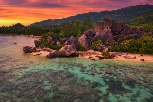 Sunset above Anse Source D'argent beach at the La Digue Island, Seychelles, with colorful clouds, palm trees and amazing granite rock formations.
