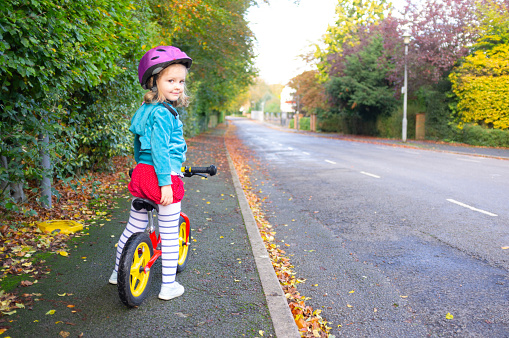 An adorable three year old girl learning to ride a bike.