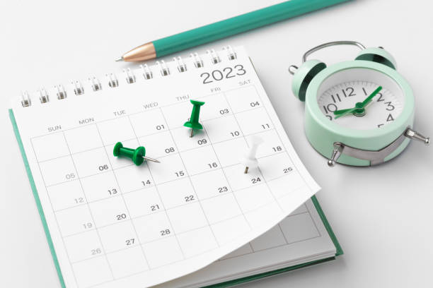 istock Scheduling and planning concept, calendar with green pin, pen and clock on white desk 1466986766
