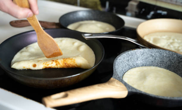 russland moskau 14.03.2021 kochen viele große leckere pfannkuchen viele pfannen, öl, pfannkuchenteig. russisches traditionelles nationalfestival winter maslenitsa ferienwoche, strovetid. mann, vater koch. familienurlaub - shrove tuesday stock-fotos und bilder