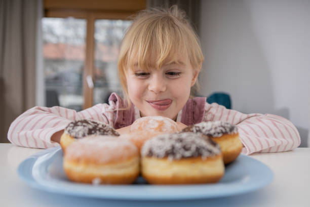 istock Cute little girl is enjoying donuts 1466989240