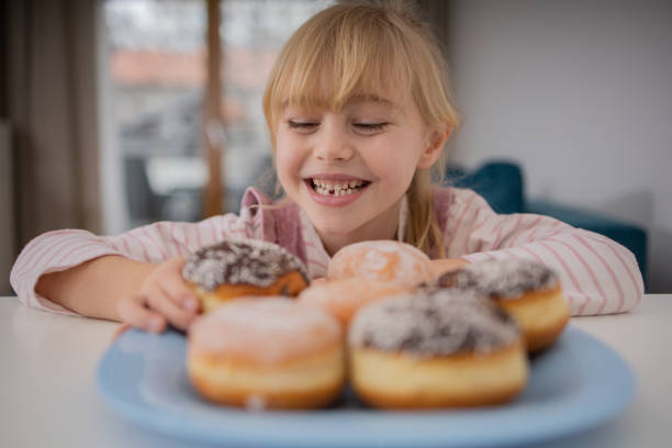 istock Cute little girl is enjoying donuts 1466989244