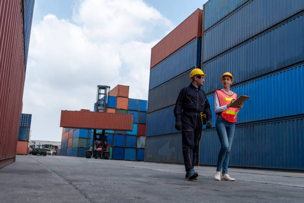 istock Industrial worker works with co-worker at overseas shipping container yard . Logistics supply chain management and international goods export concept . 1466990558