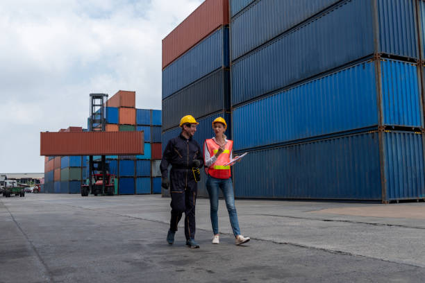 istock Industrial worker works with co-worker at overseas shipping container yard . Logistics supply chain management and international goods export concept . 1466990680