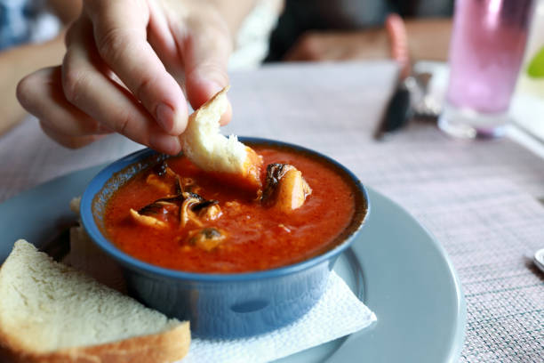 istock Person dipping bread into tomato sauce with mussels 1466991135
