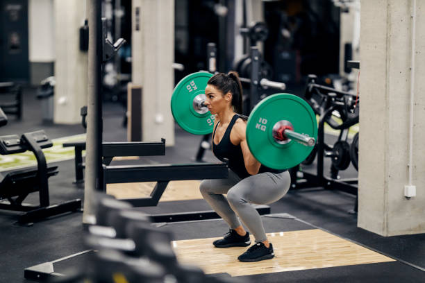 istock A strong female bodybuilder is lifting weights in a gym while squatting. 1466991148