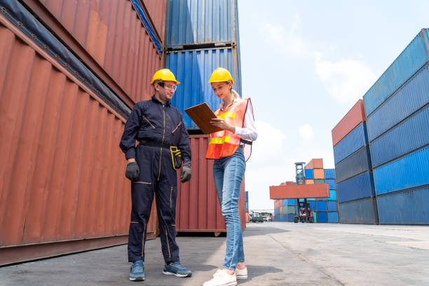 istock Industrial worker works with co-worker at overseas shipping container yard . Logistics supply chain management and international goods export concept . 1466991154