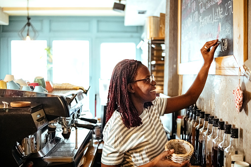 Confident female barista works on coffee order