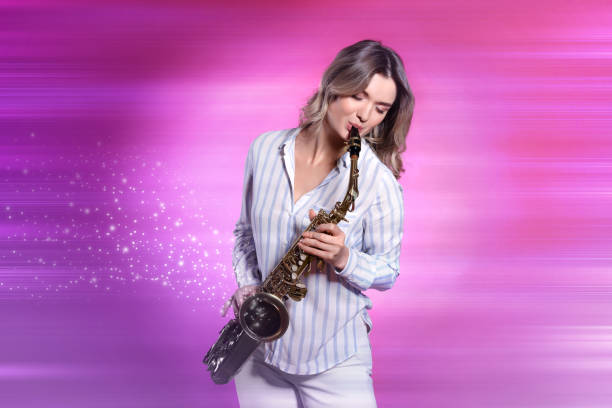 istock Beautiful young woman playing saxophone on pink background 1466993554