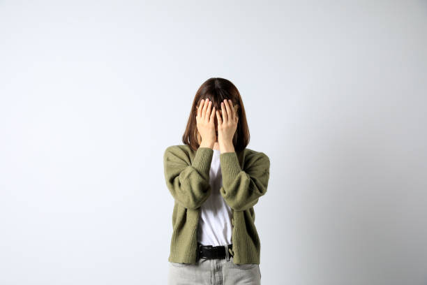 istock Young girl hiding face in hands on white background 1466993898