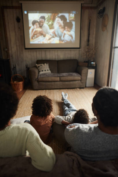 widok z tyłu czarnej rodziny oglądającej film w domu. - projection equipment home interior house living room zdjęcia i obrazy z banku zdjęć