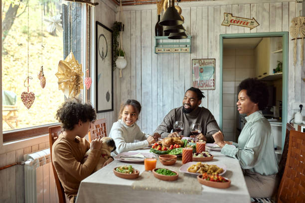 Happy black family talking during lunch at dining table.
