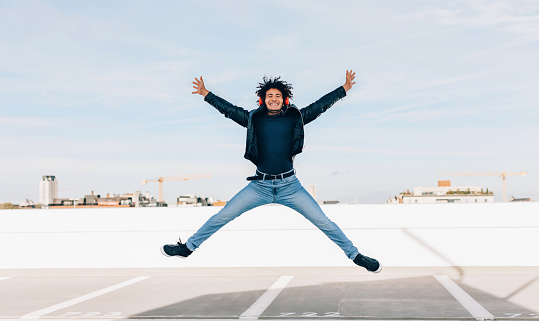 overjoyed young casual man jumping for joy with legs and arms outstretched