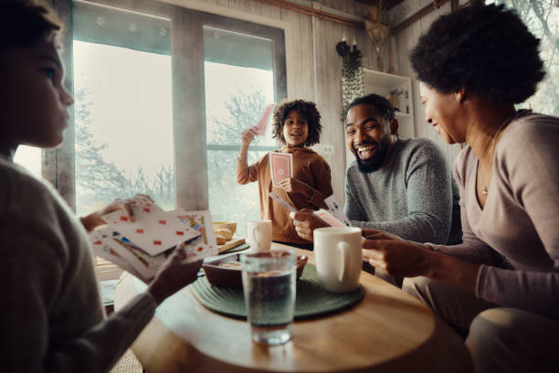 Happy African American family playing cards at home. Happy black parents and their small kids playing cards in the living room. friends playing cards stock pictures, royalty-free photos & images