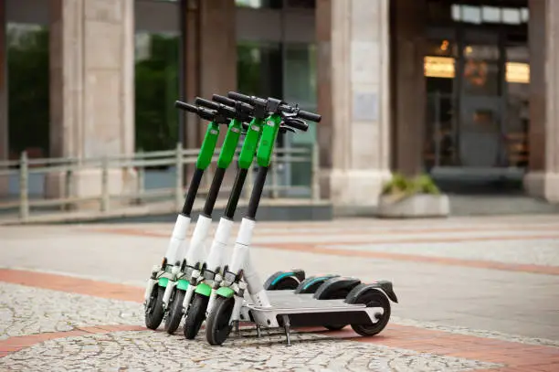 Row of electric scooters on city street. Rental service
