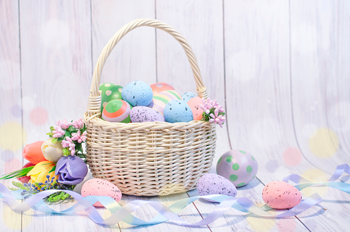 wicker basket with painted Easter eggs on a light background, Easter composition, Easter card. High quality photo