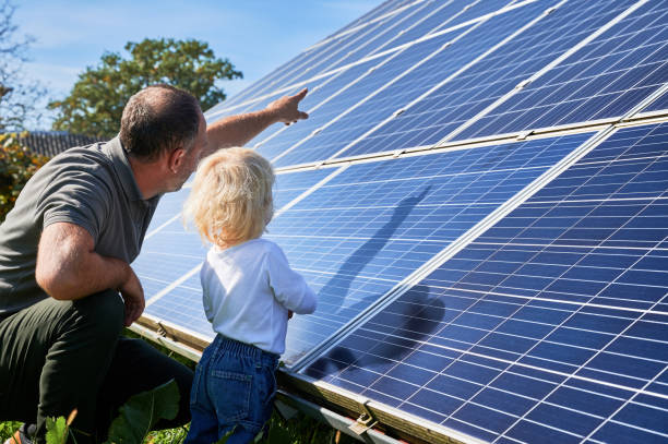 istock Man shows his small child the solar panels during warm day 1466998603