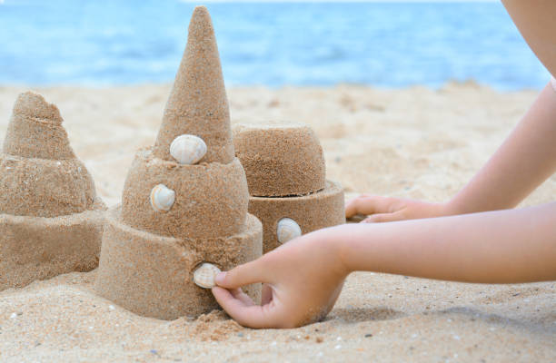 istock Child decorating sand castle with shell on beach, closeup 1466998905